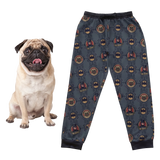 Pug sitting next to a sweatpants with a batman pattern on a white background