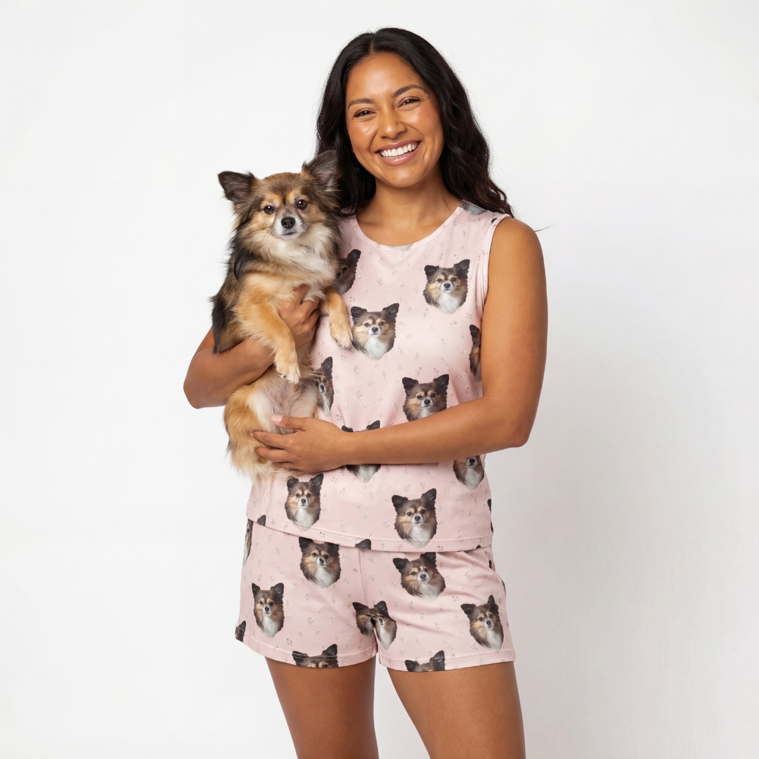 Woman wearing tank top pajamas with cat prints, holding a small dog.
