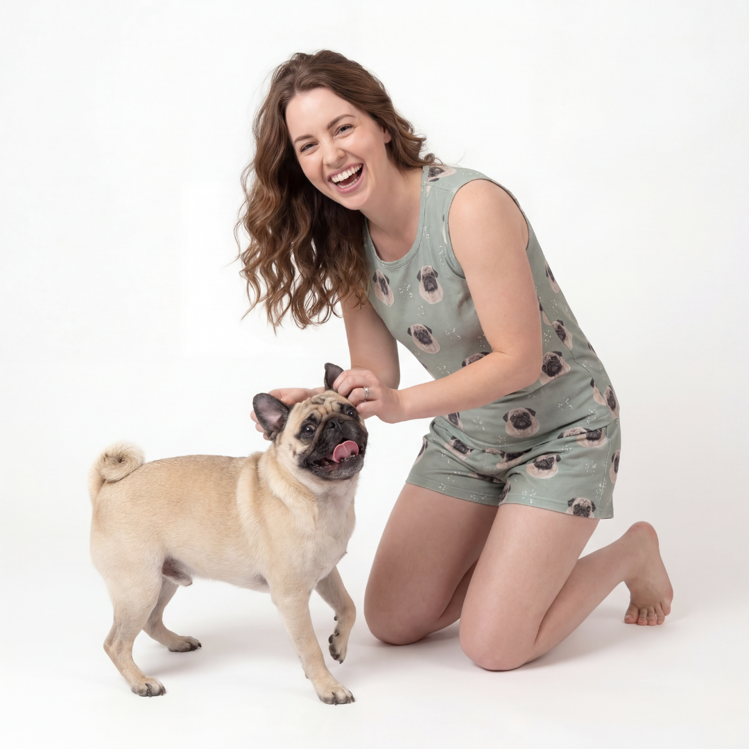 Woman wearing tank top pajamas set kneeling next to a pug on a white background