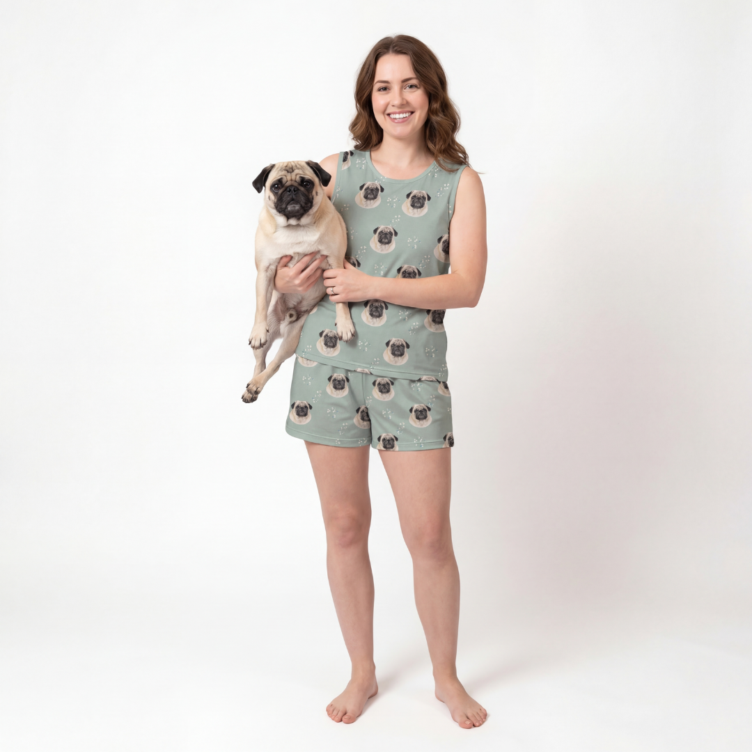 Woman wearing tank top pajamas with a pug-patterned  holding a pug on a white background