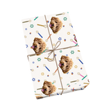 White Hanukkah pet wrapping paper with dog portraits, symbols, and gold ribbon.