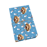Light blue pet wrapping paper with dog portraits, snowmen, snowflakes, and golden ribbon
