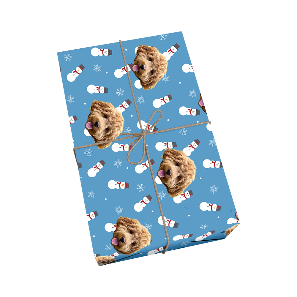 Custom pet wrapping paper in light blue featuring repeating pattern of dog portraits with cheerful snowmen with red scarves and orange carrots nose, and white snowflakes with golden ribbon design